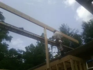Carpenter setting a ridge beam over a new addition frame — Ice Dam Removal by Roofing Brothers in Rocky