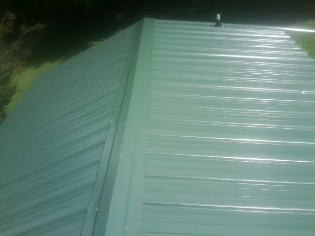 New green metal panels meeting at the ridge of a roof — Flat Roof Repair work by our crew in Rocky