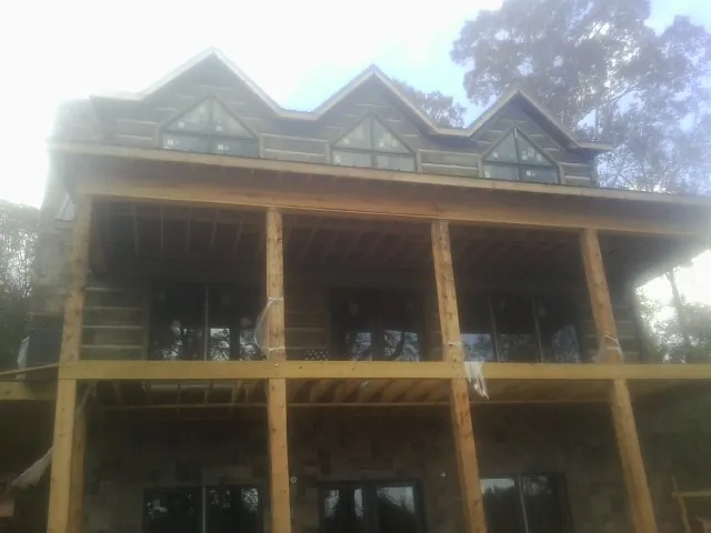 Dormers and porch framing on a large log home under construction — Roof Coating work by our crew in Rocky