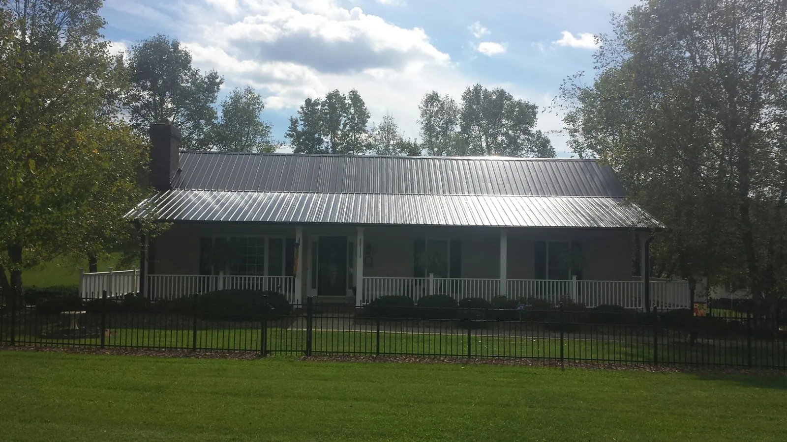 Gray metal roof on a brick ranch with a full width front porch — Gutter Guard Installation work by our crew in Rocky
